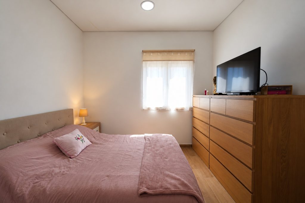 Quarto principal com cómoda em madeira e luz natural, moradia térrea no Barreiro