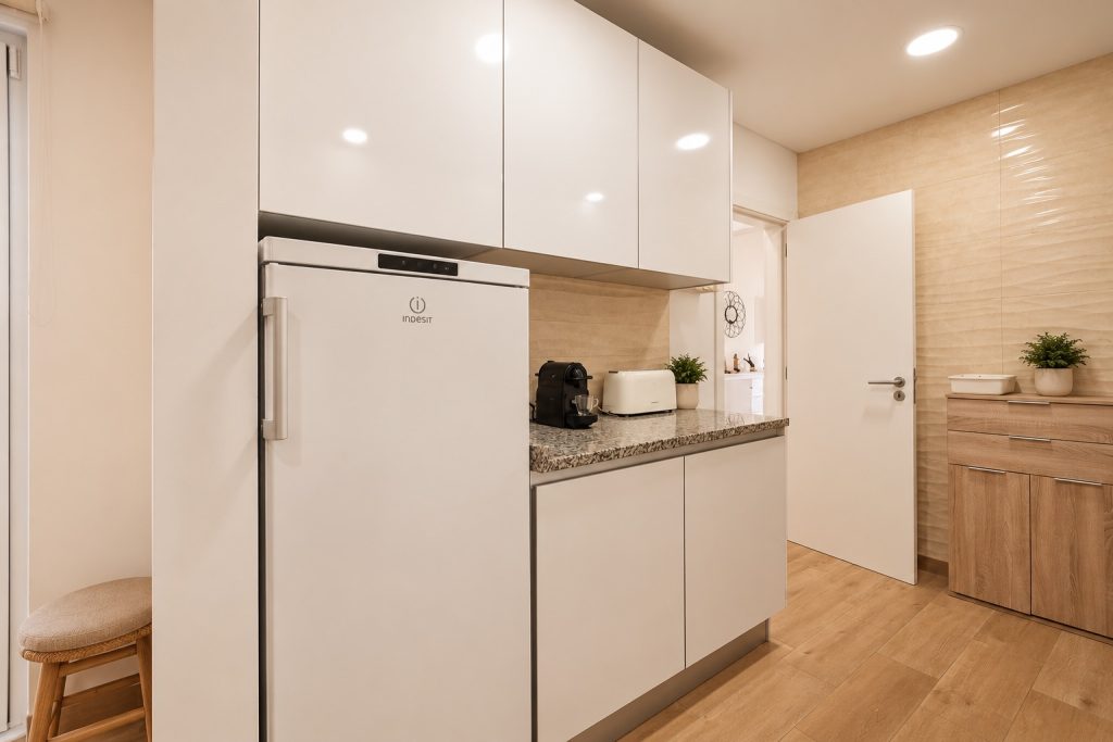 Cozinha com frigorífico e armários brancos lacados, moradia T2 em Santo André, Barreiro