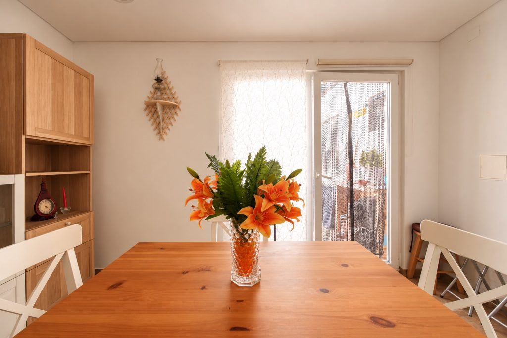 Zona de refeições com mesa em madeira e luz natural, moradia T2 em Santo André, Barreiro